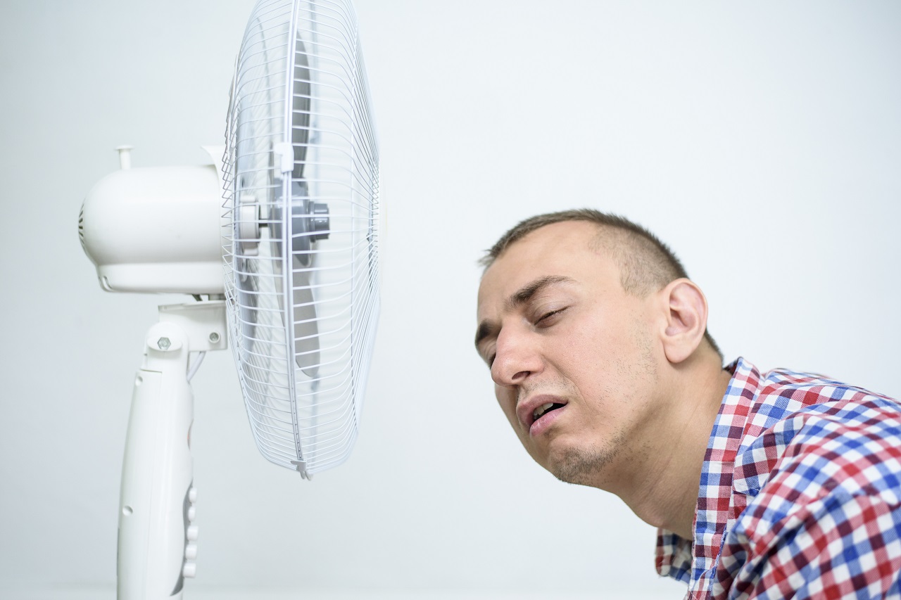 A man near a fan due to the extreme heat