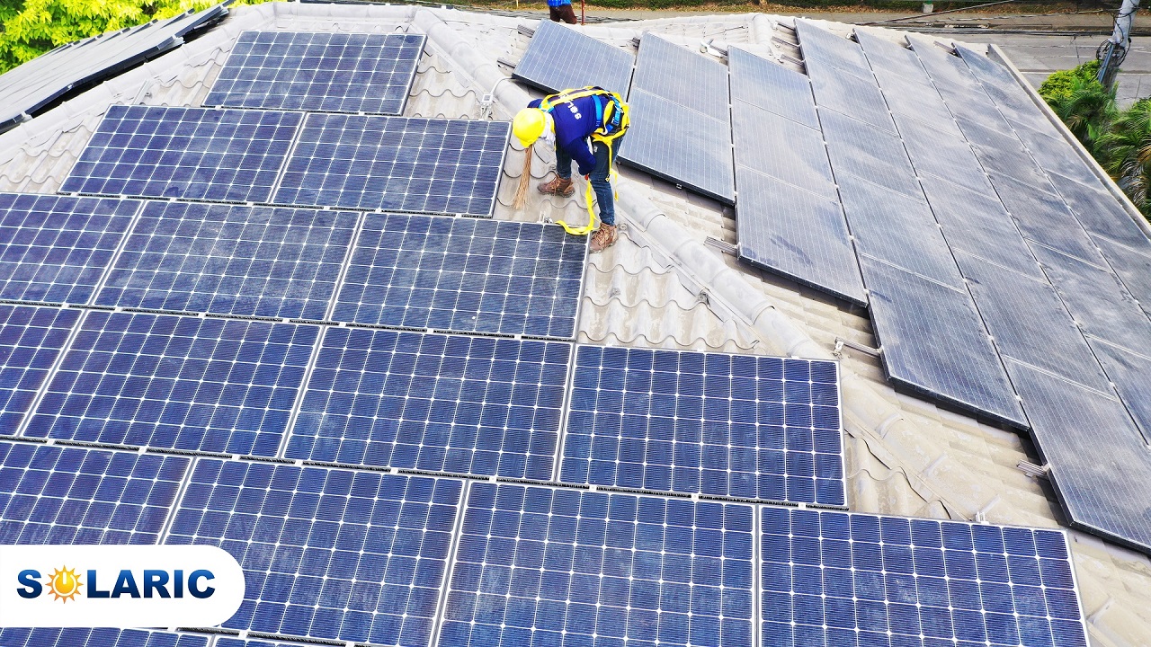 A man sweeping volcanic ash off of solar panels